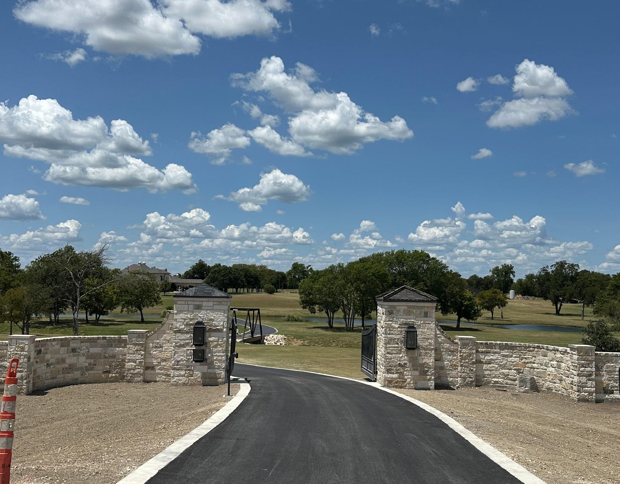 Straight-on view of the limestone gate columns, lanterns, and iron gate, Temple TX